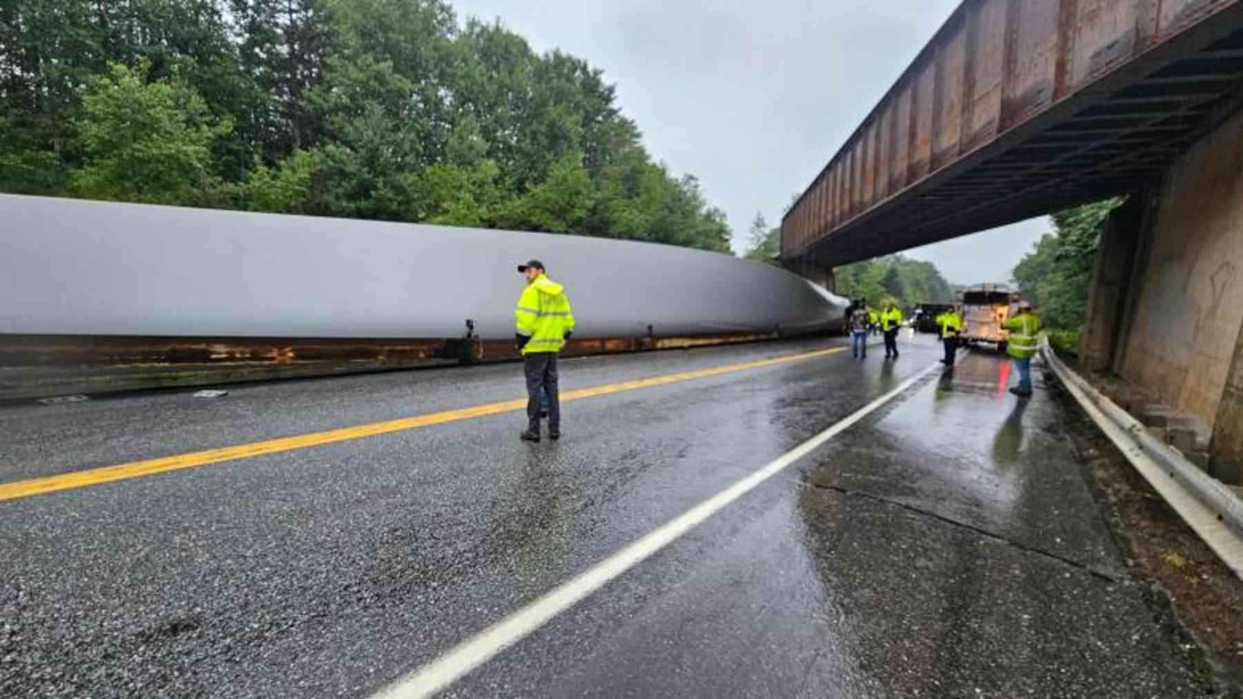 Overturned tractor-trailer with a 240-foot turbine blade across Route 1 after hitting a railroad trestle in Maine